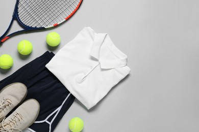 Photo of Tennis racket, balls, sneakers and sportswear on grey background, flat lay. Space for text