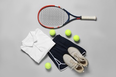 Photo of Tennis racket, balls, sneakers and sportswear on grey background, flat lay