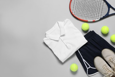 Photo of Tennis racket, balls, sneakers and sportswear on grey background, flat lay. Space for text