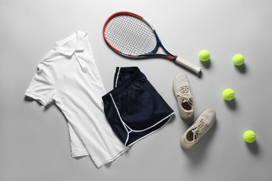 Photo of Tennis racket, balls, sneakers and sportswear on grey background, flat lay