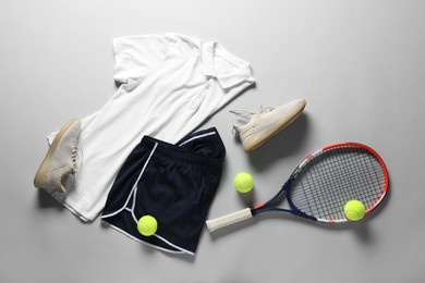 Photo of Tennis racket, balls, sneakers and sportswear on grey background, flat lay