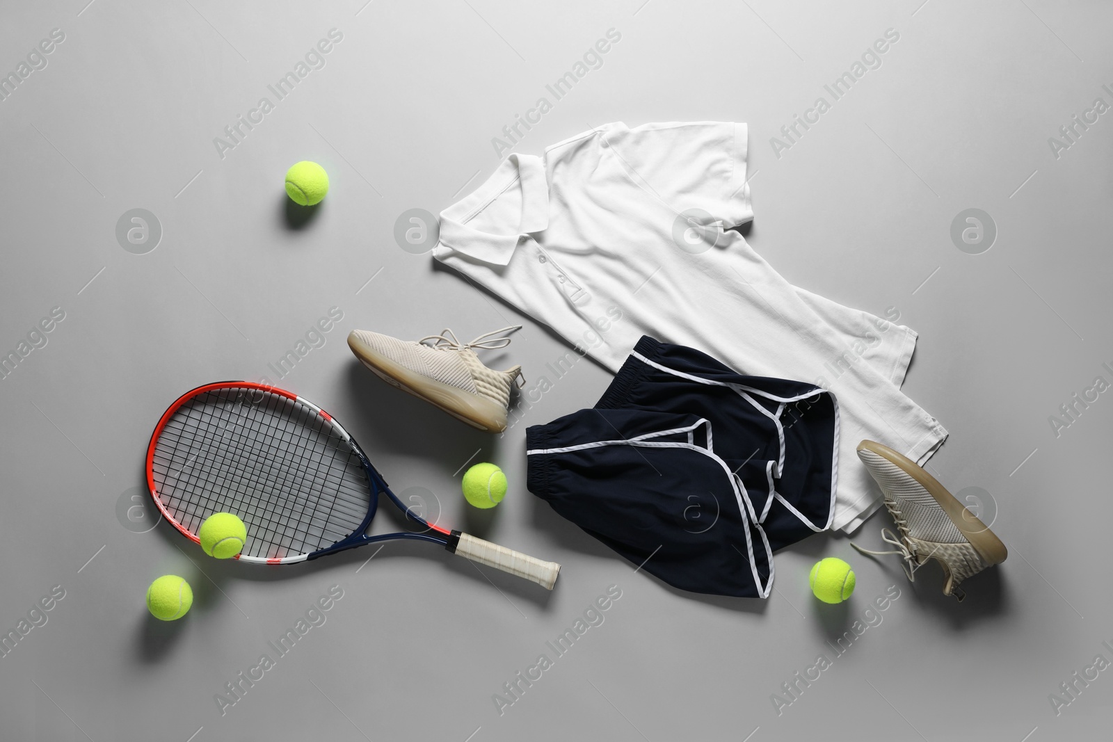 Photo of Tennis racket, balls, sneakers and sportswear on grey background, flat lay