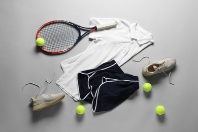 Photo of Tennis racket, balls, sneakers and sportswear on grey background, flat lay