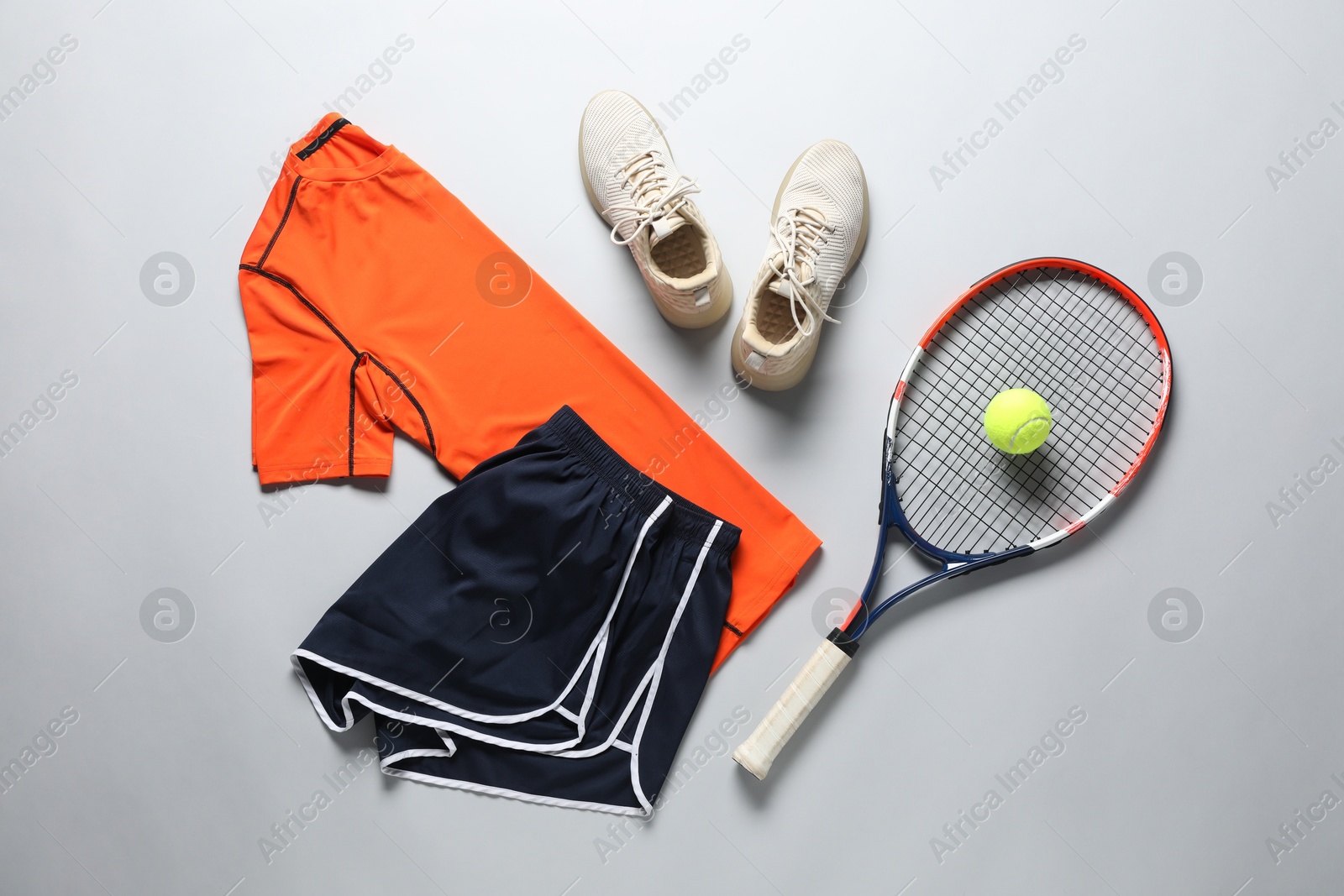 Photo of Tennis racket, ball, sneakers and sportswear on grey background, flat lay