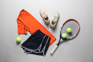 Photo of Tennis racket, balls, sneakers and sportswear on grey background, flat lay