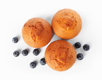 Photo of Delicious sweet muffins and blueberries isolated on white, top view