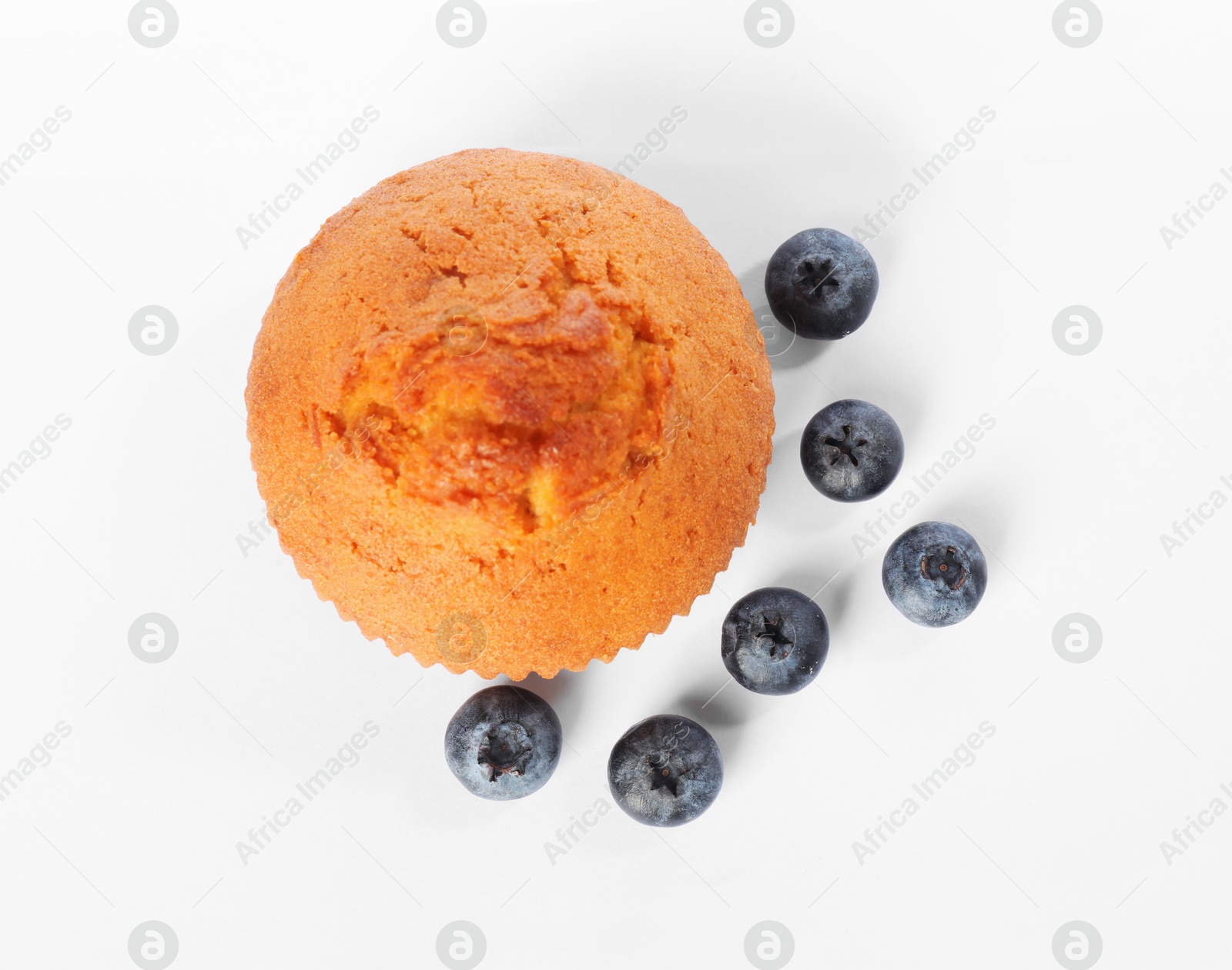 Photo of Delicious sweet muffin and blueberries isolated on white, top view