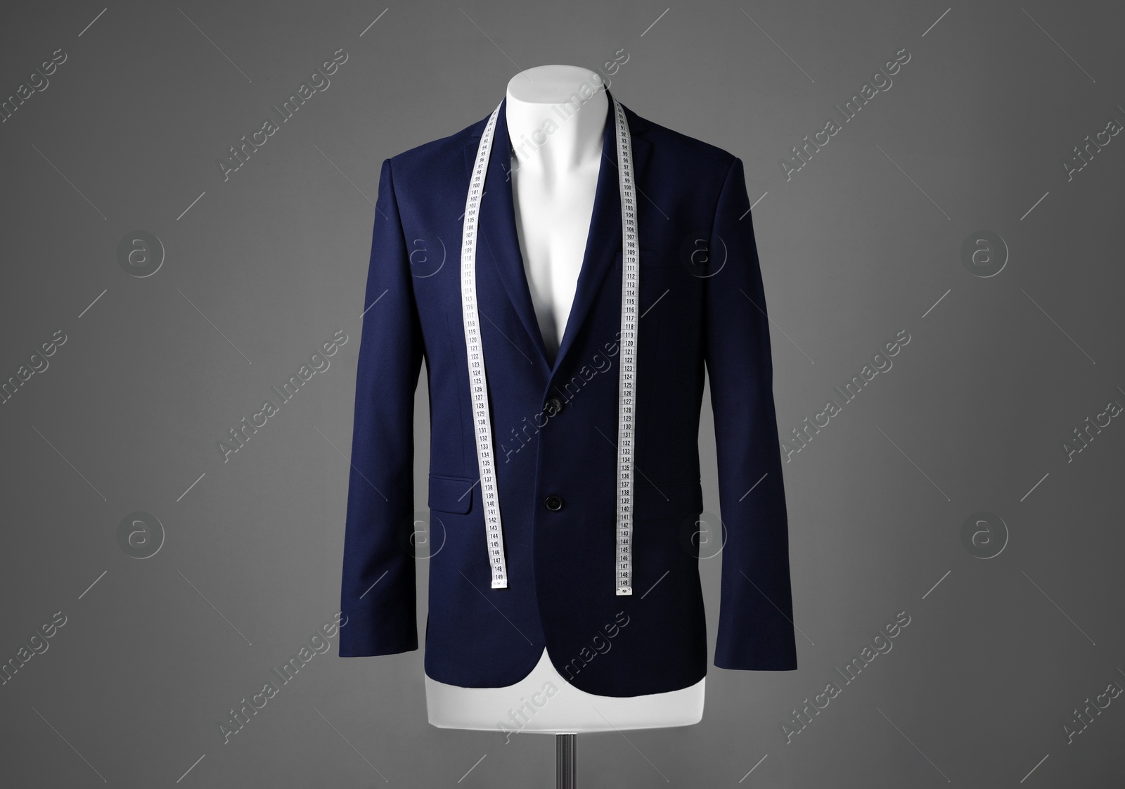 Photo of Male mannequin with blue jacket and measuring tape on grey background