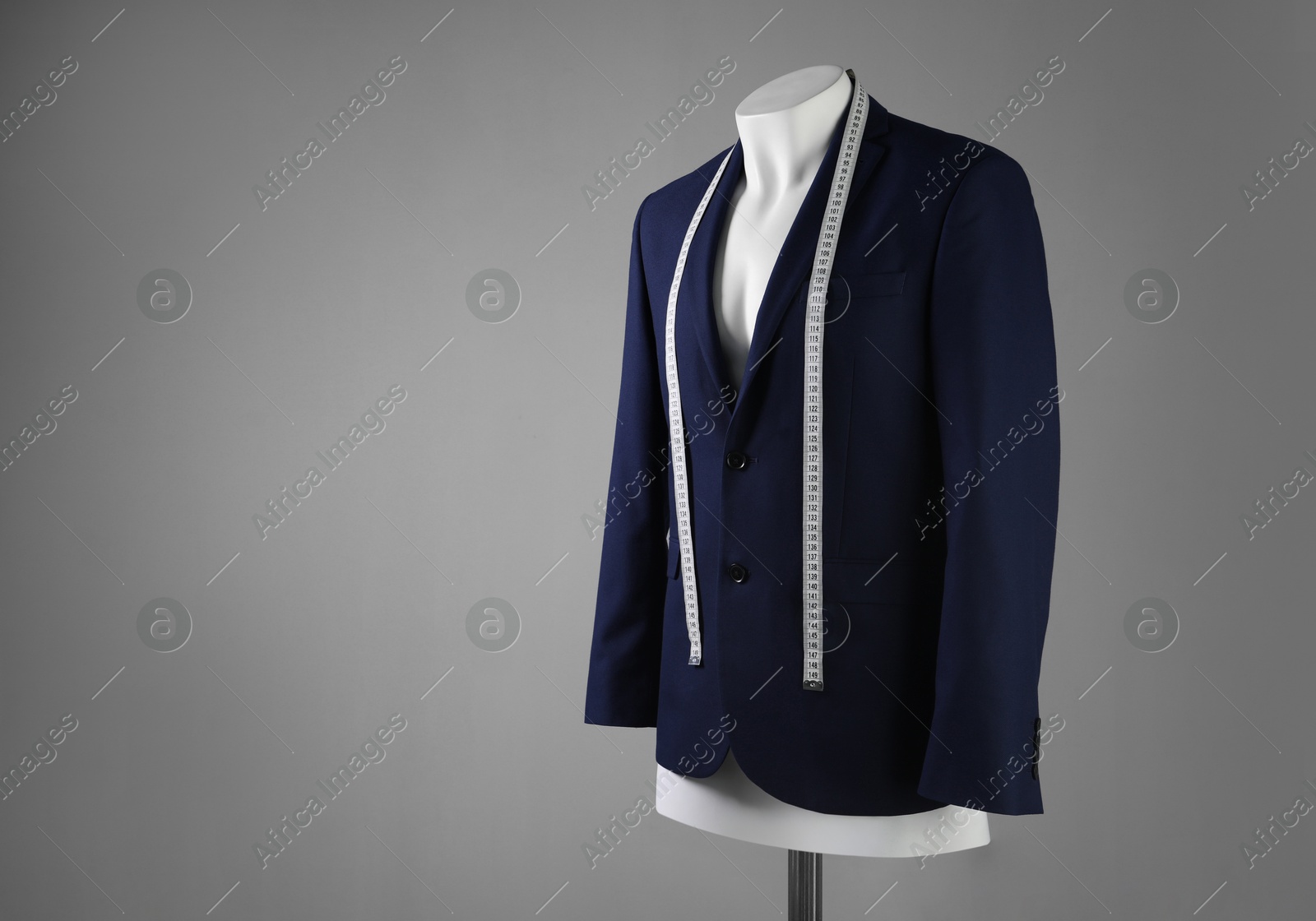 Photo of Male mannequin with blue jacket and measuring tape on grey background, space for text