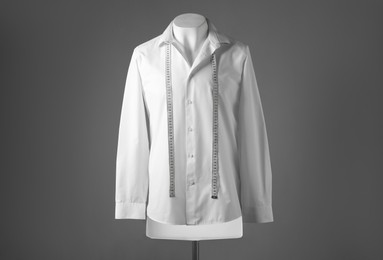 Male mannequin with white shirt and measuring tape on grey background