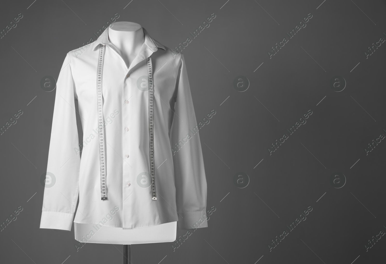 Photo of Male mannequin with white shirt and measuring tape on grey background, space for text