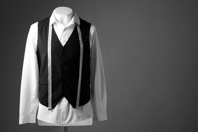 Photo of Male mannequin with black vest, white shirt and measuring tape on grey background, space for text