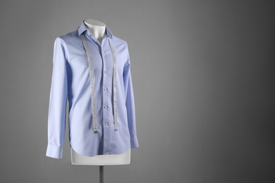 Photo of Male mannequin with light blue shirt and measuring tape on grey background, space for text