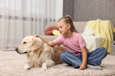 Girl with her cute Golden Retriever dog on rug at home