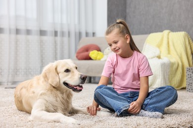 Girl with her cute Golden Retriever dog on rug at home