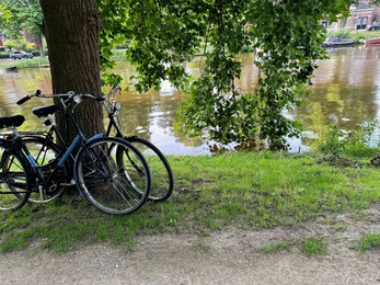 Photo of Bicycles parked at tree near canal outdoors