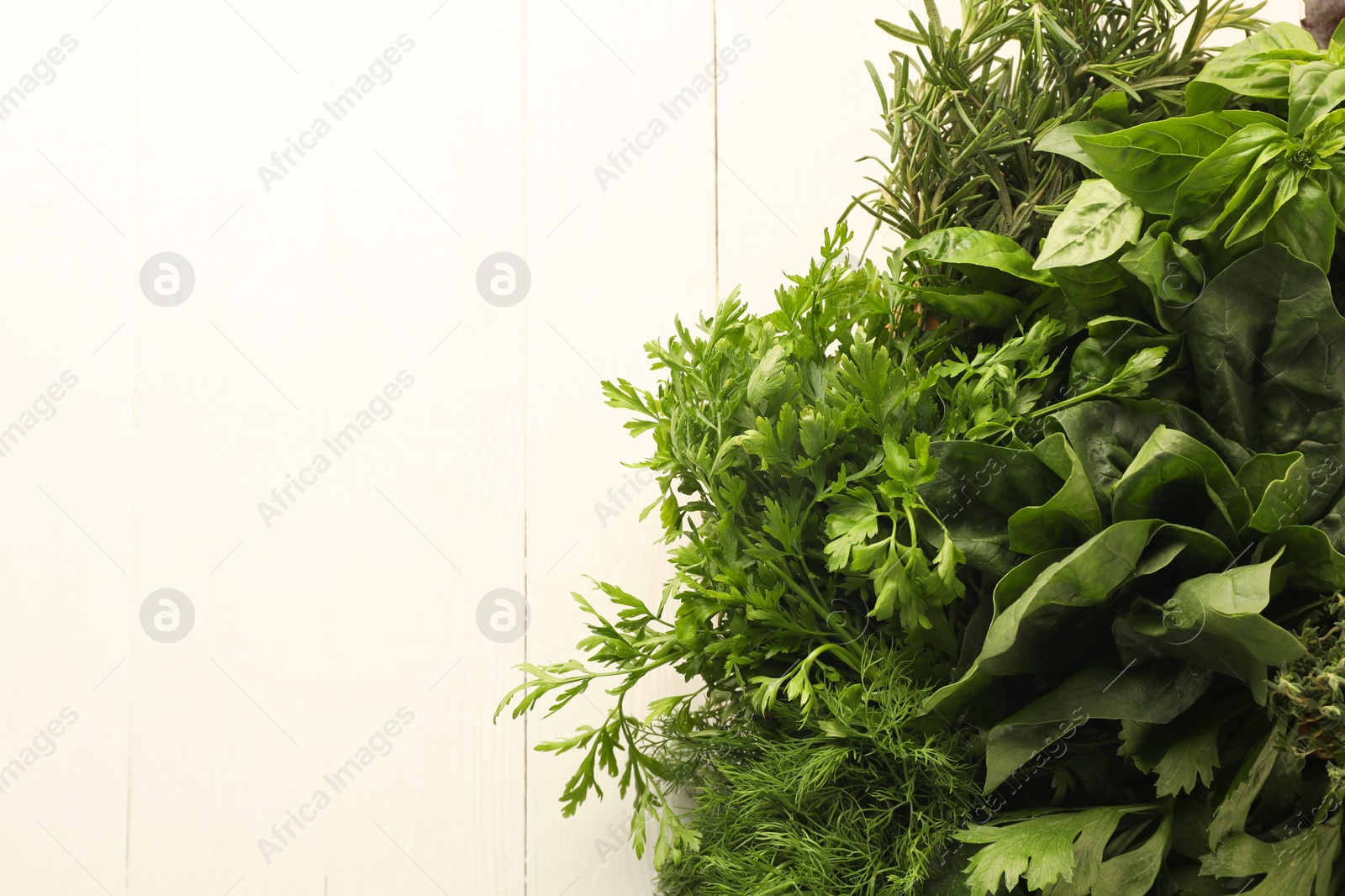 Photo of Different fresh herbs in basket on white wooden table, top view. Space for text