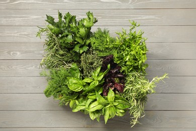 Photo of Different fresh herbs in basket on light grey wooden table, top view