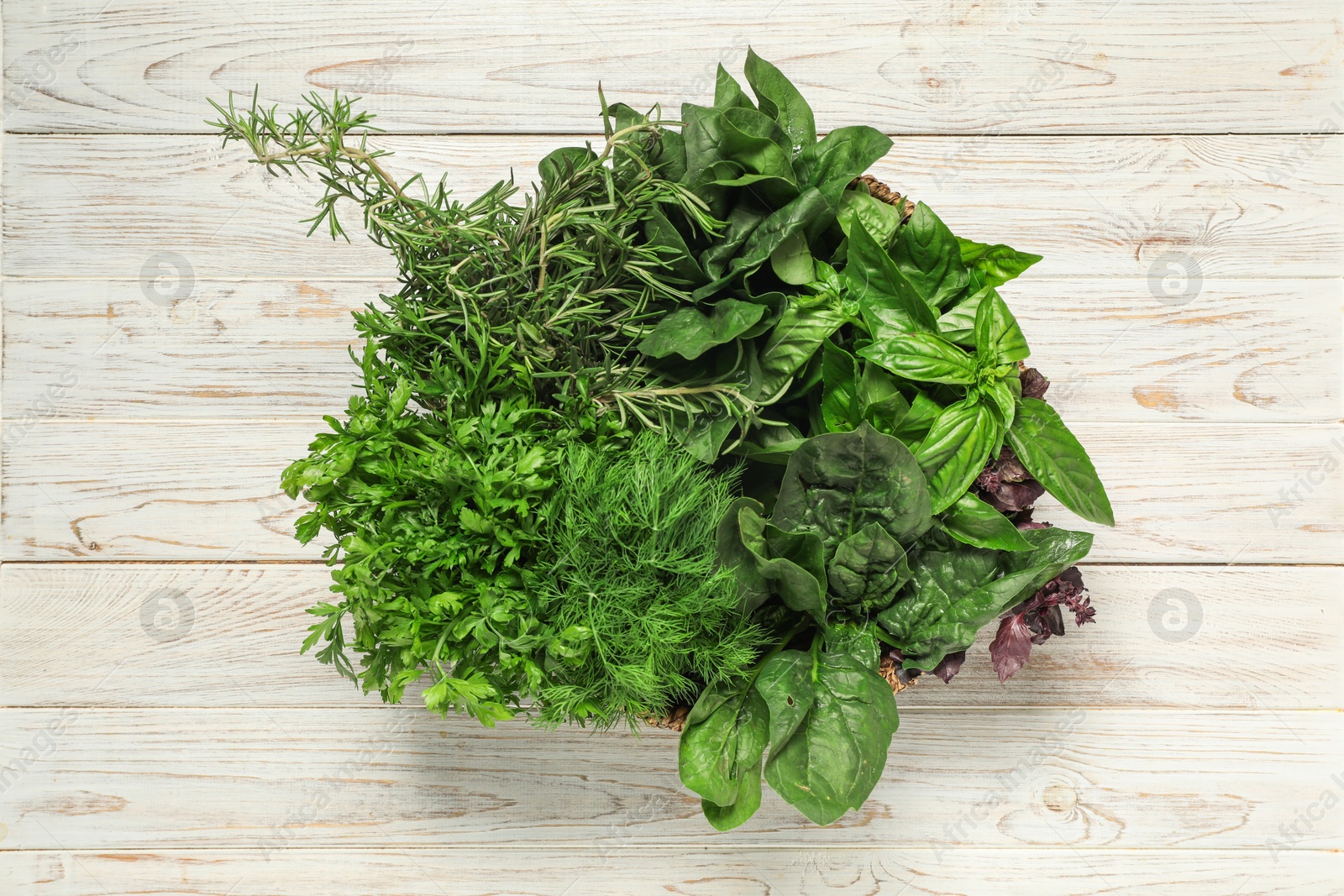 Photo of Different fresh herbs in basket on white wooden table, top view