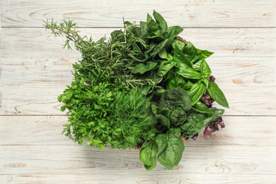 Photo of Different fresh herbs in basket on white wooden table, top view