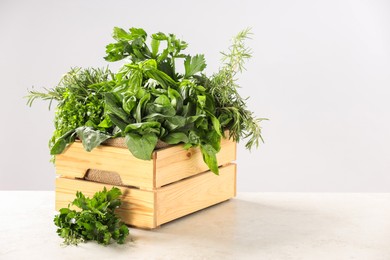 Photo of Different fresh herbs in wooden basket on white table. Space for text