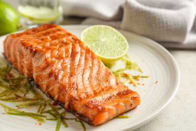 Photo of Delicious grilled salmon fillet served on light table, closeup