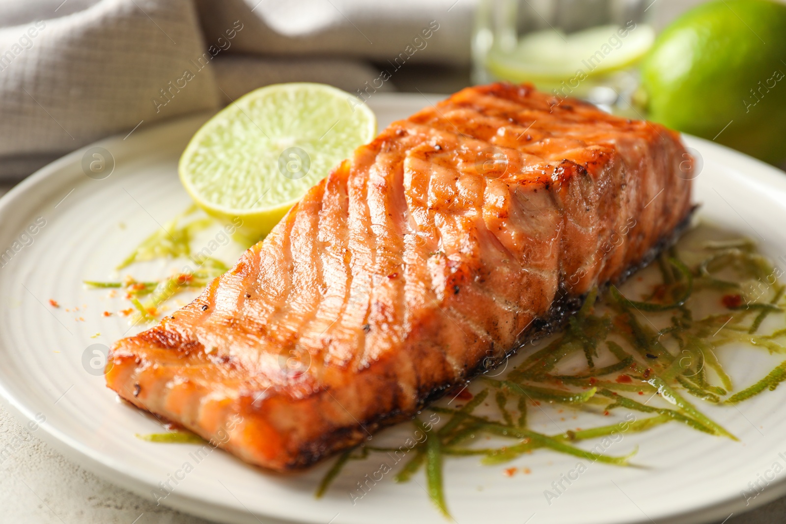 Photo of Delicious grilled salmon fillet served on light table, closeup