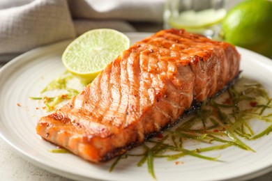 Photo of Delicious grilled salmon fillet served on light table, closeup