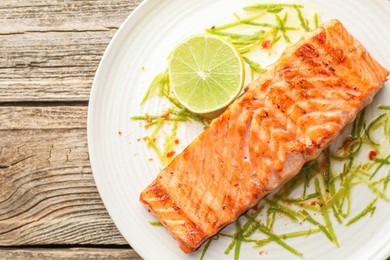 Photo of Delicious grilled salmon fillet served on wooden table, top view