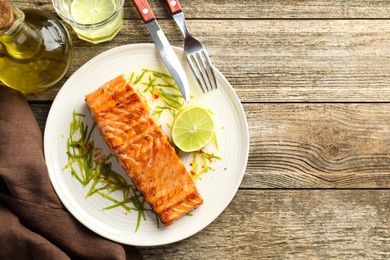 Photo of Delicious grilled salmon fillet served on wooden table, flat lay