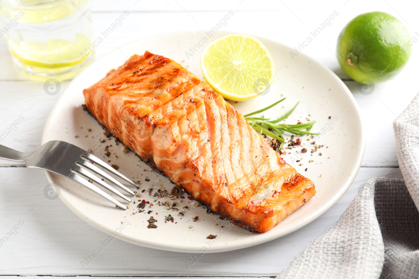 Photo of Delicious grilled salmon fillet served on white wooden table, closeup