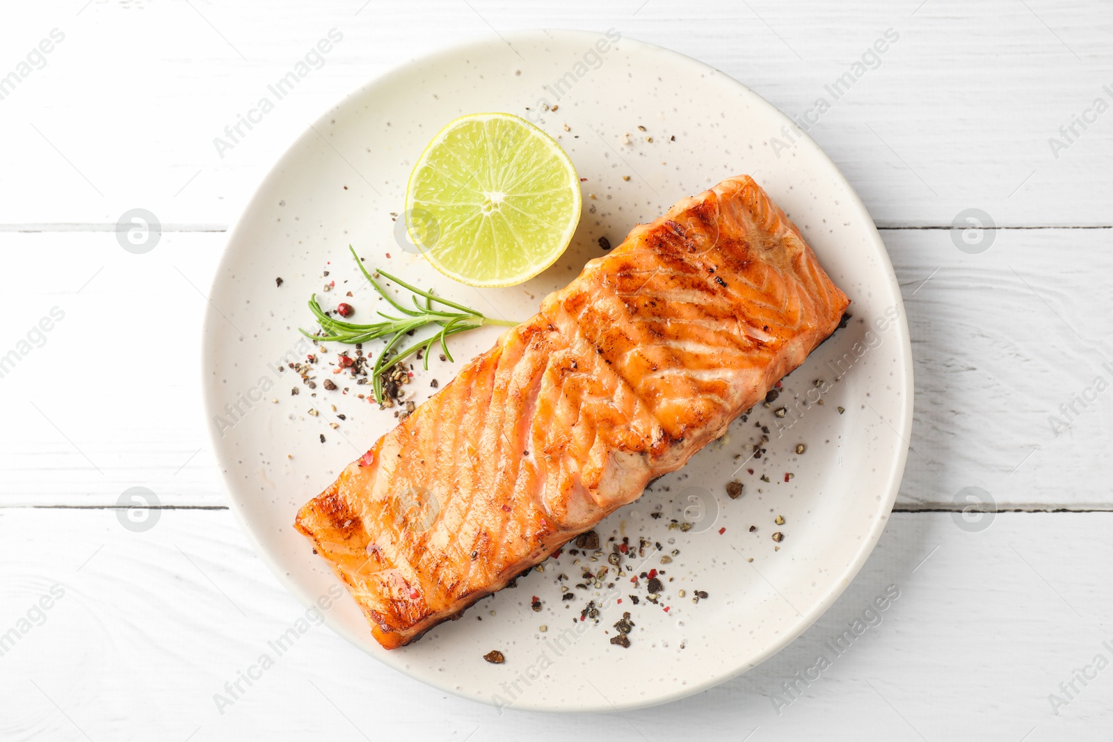 Photo of Delicious grilled salmon fillet served on white wooden table, top view