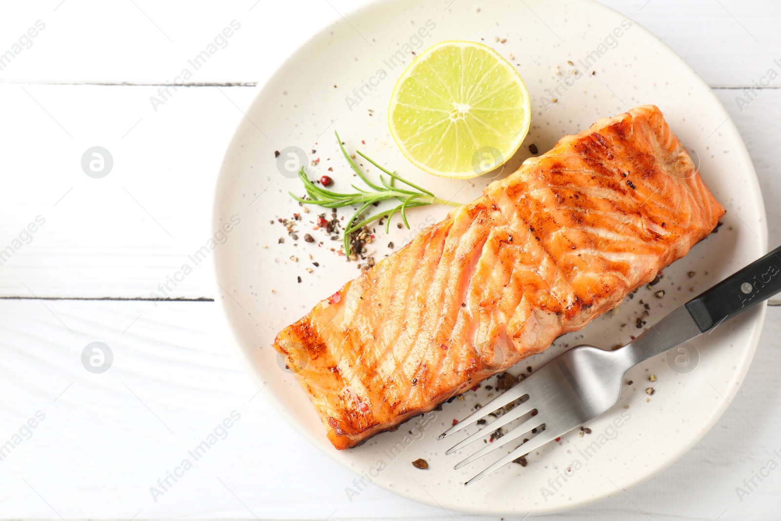 Photo of Delicious grilled salmon fillet served on white wooden table, top view