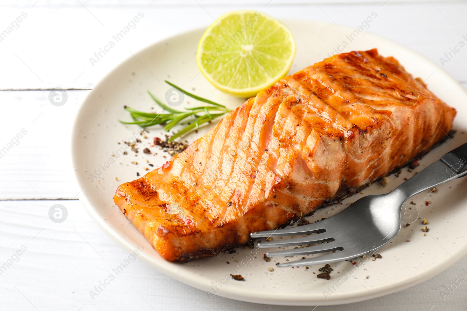 Photo of Delicious grilled salmon fillet served on white wooden table, closeup