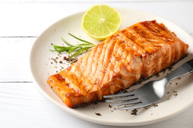 Photo of Delicious grilled salmon fillet served on white wooden table, closeup