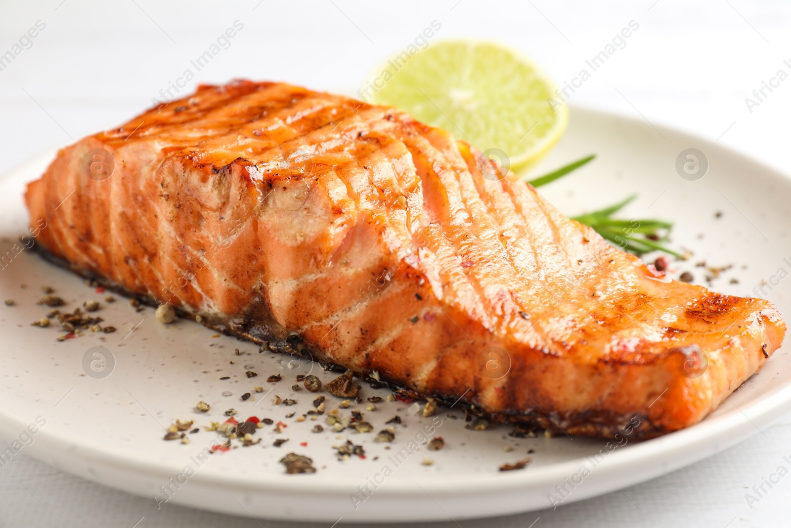 Photo of Delicious grilled salmon fillet served on white wooden table, closeup