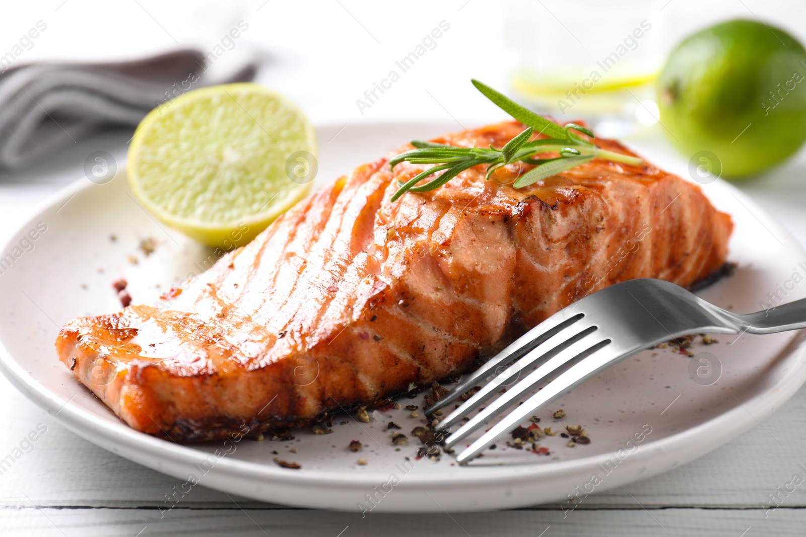 Photo of Delicious grilled salmon fillet served on white wooden table, closeup