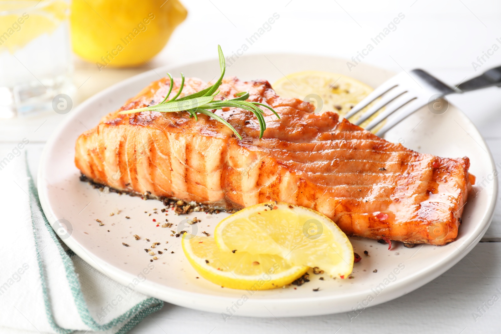 Photo of Delicious grilled salmon fillet served on white wooden table, closeup