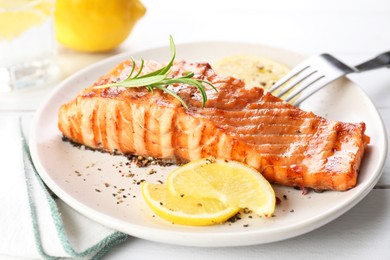 Photo of Delicious grilled salmon fillet served on white wooden table, closeup