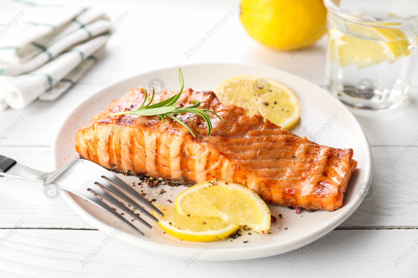 Photo of Delicious grilled salmon fillet served on white wooden table, closeup