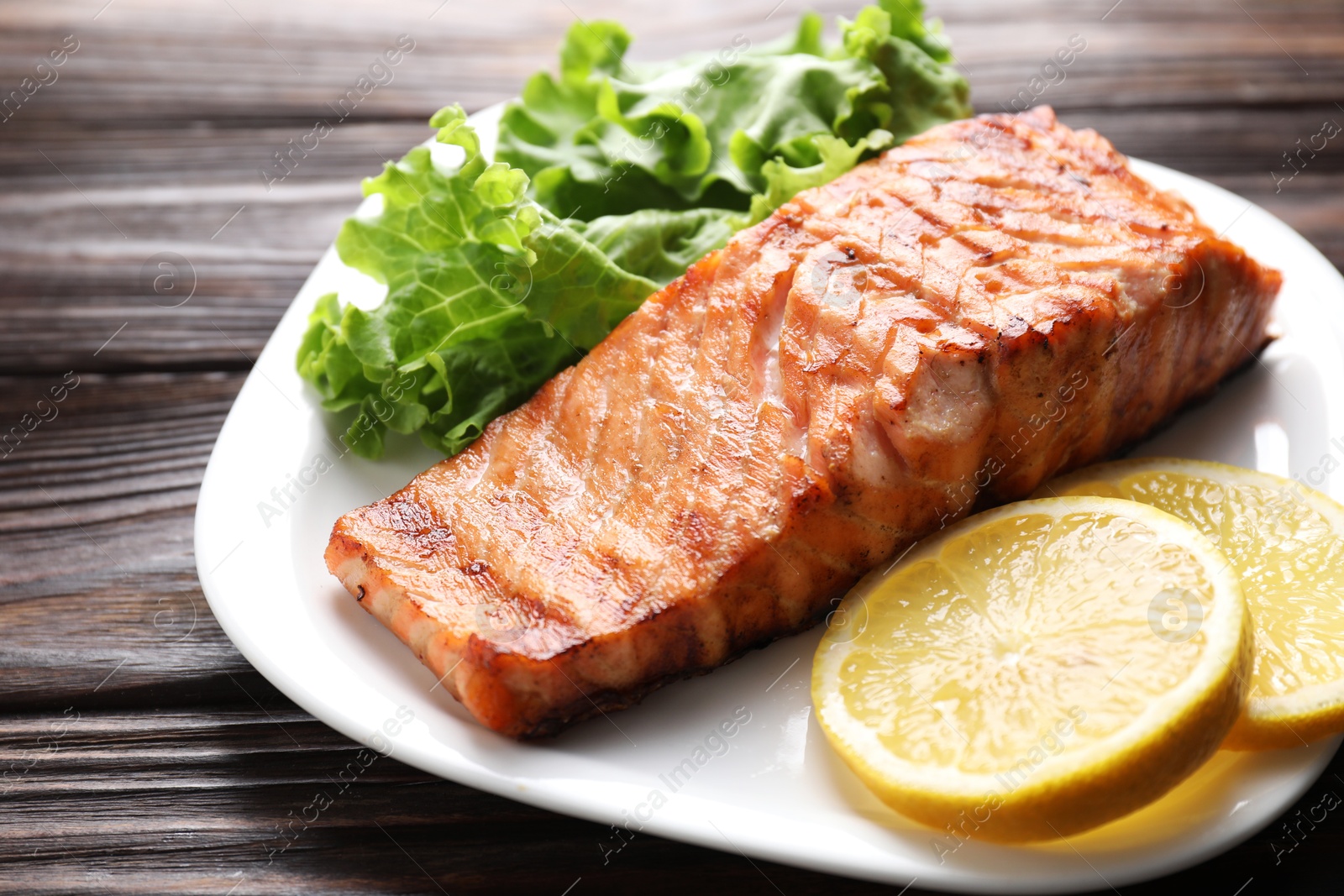 Photo of Delicious grilled salmon fillet served on wooden table, closeup