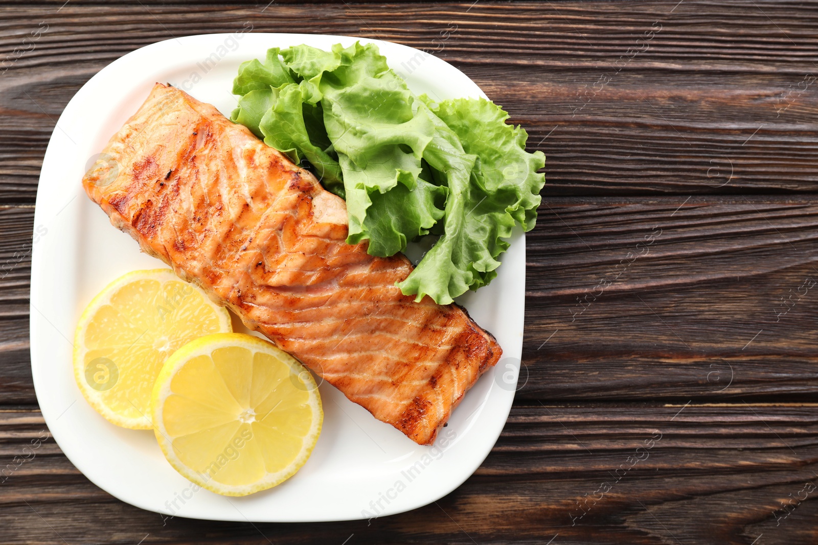 Photo of Delicious grilled salmon fillet served on wooden table, top view