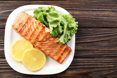 Photo of Delicious grilled salmon fillet served on wooden table, top view