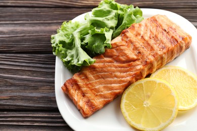 Photo of Delicious grilled salmon fillet served on wooden table, closeup