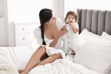 Photo of Beautiful young mother and her cute little baby with rattle on bed at home