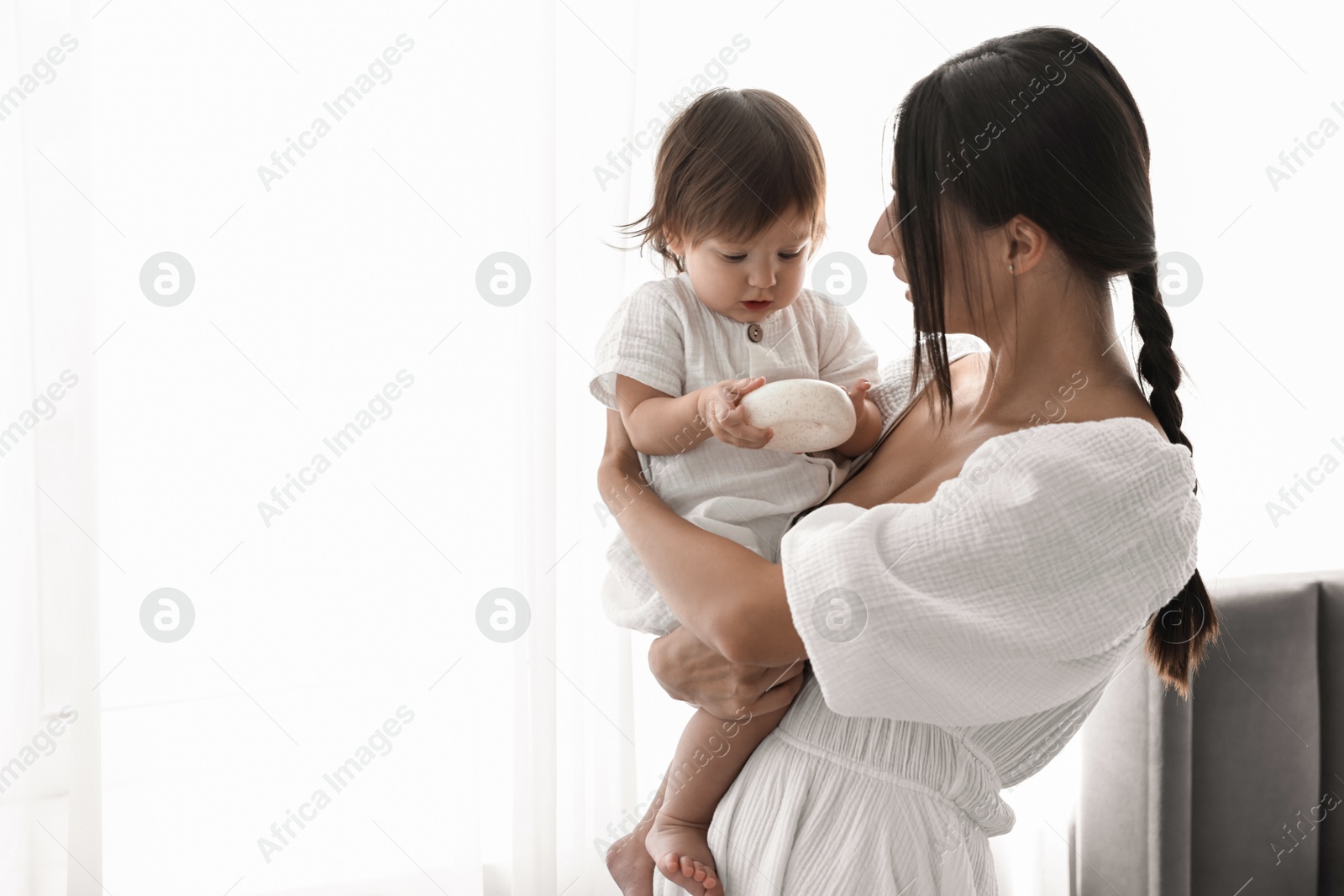 Photo of Beautiful young mother with her cute little baby indoors, space for text