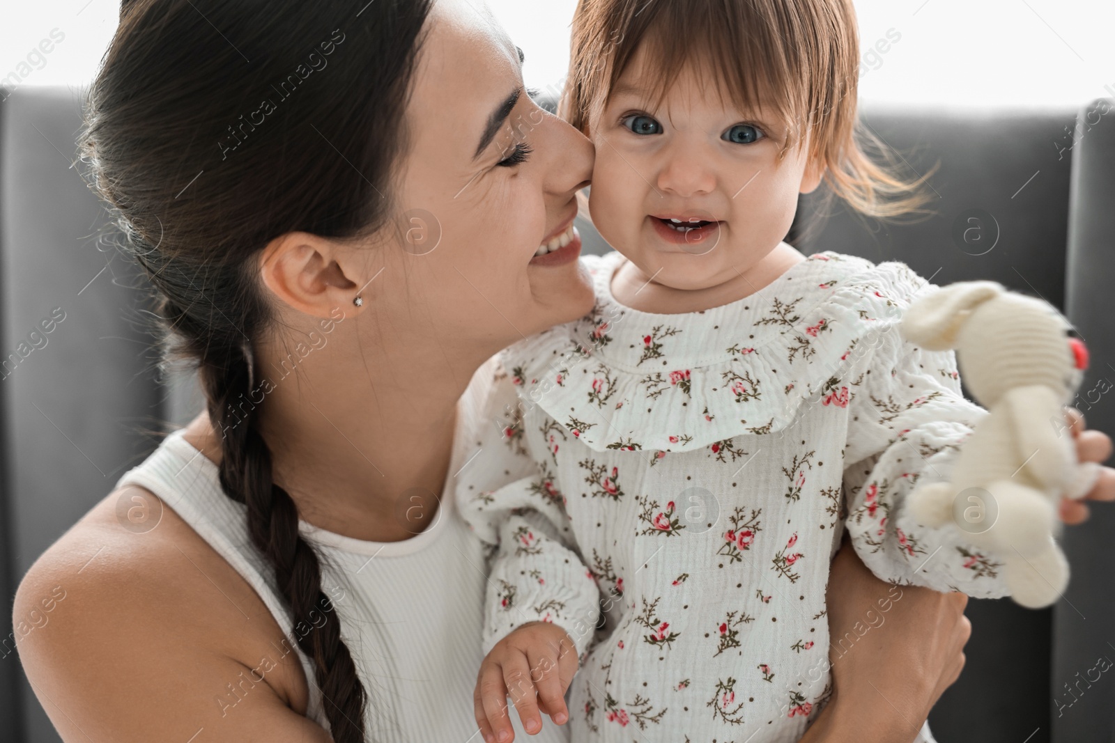 Photo of Beautiful young mother and her cute little baby with rabbit toy indoors