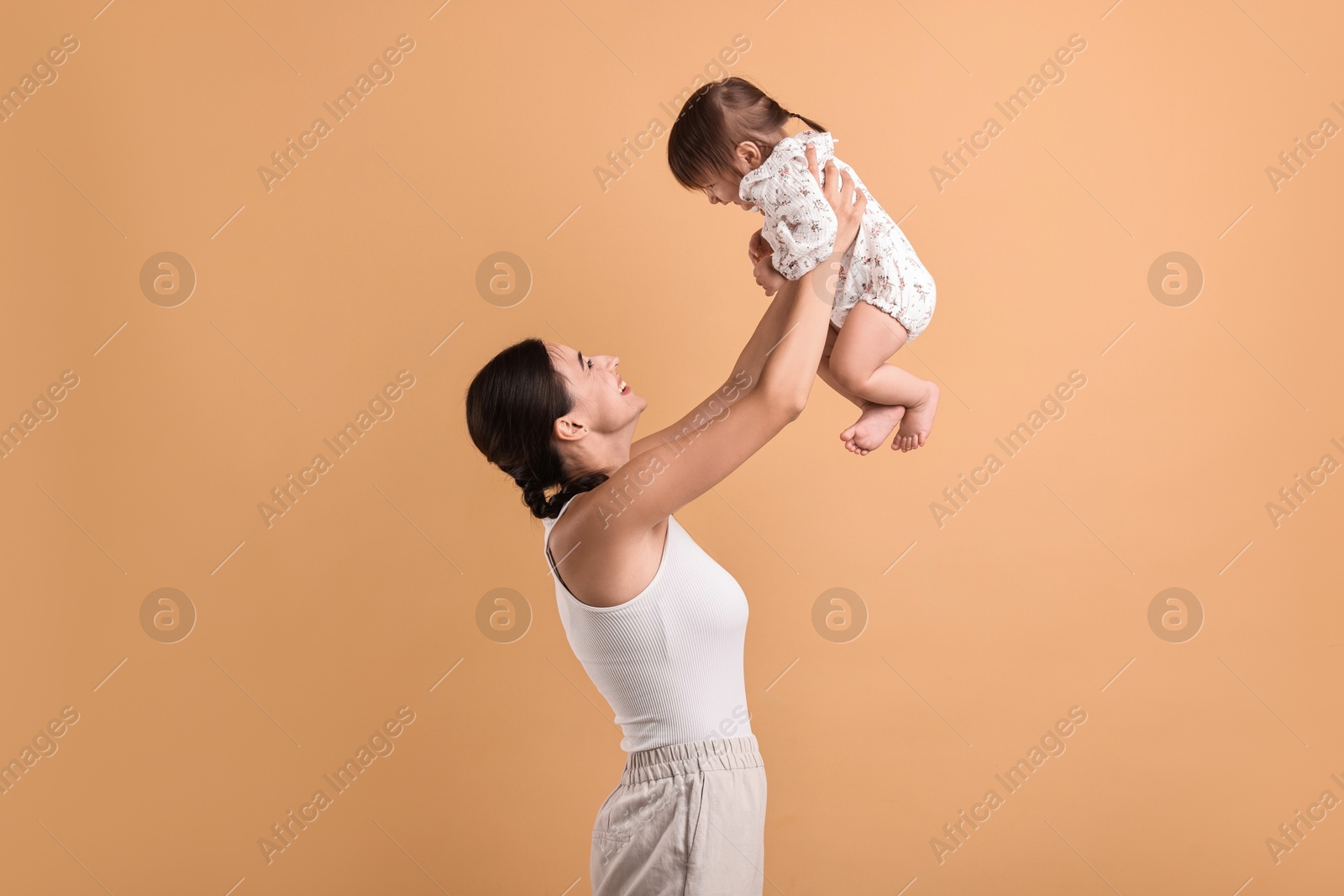 Photo of Beautiful young mother and her cute little baby on beige background