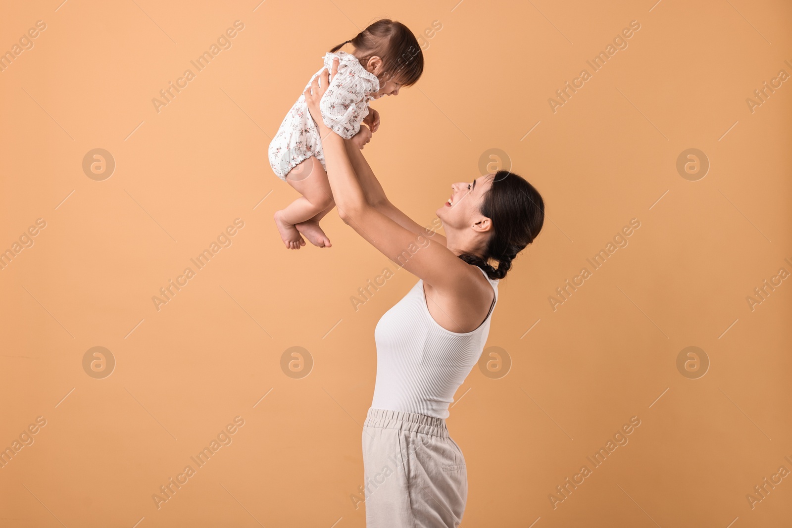 Photo of Beautiful young mother and her cute little baby on beige background