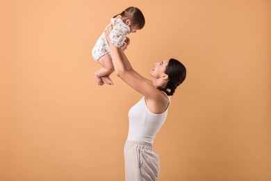 Beautiful young mother and her cute little baby on beige background